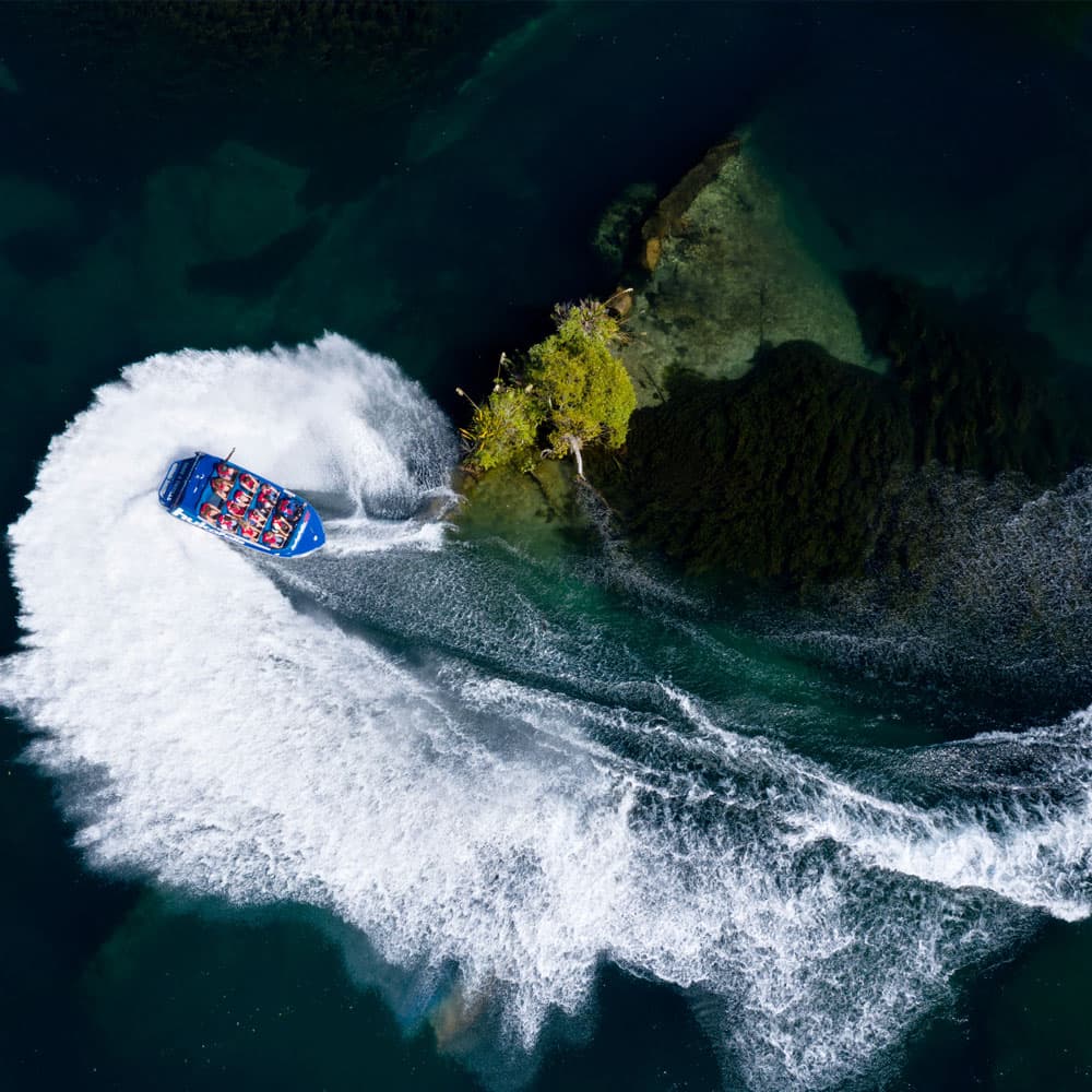 Aerial view of Huka Falls Jet boat performing a thrilling 360-degree spin on Waikato River in Taupō, New Zealand.